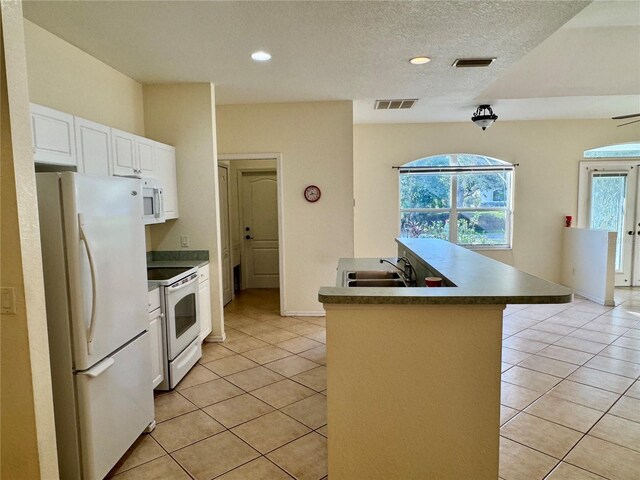 1483 Prairie Ter, North Port, FL 34286 - kitchen with white appliances, a sink, light tile patterned flooring, white cabinets, and a center island with sink