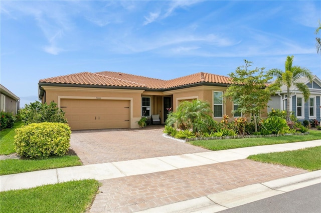view of front of house with stucco siding, decorative driveway, an attached garage, and a tile roof