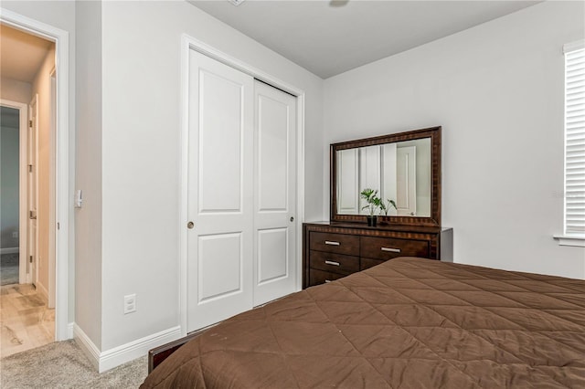 carpeted bedroom featuring a closet and baseboards