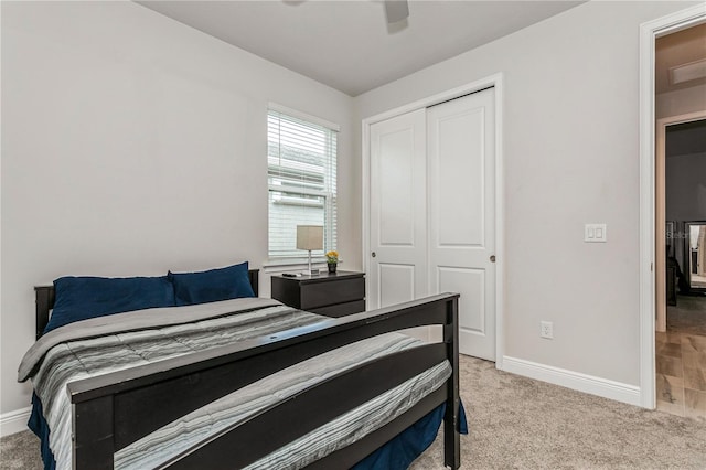bedroom featuring a closet, baseboards, light colored carpet, and a ceiling fan