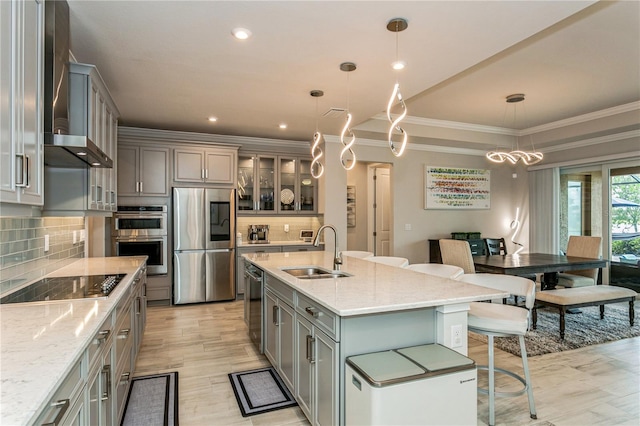kitchen with a sink, appliances with stainless steel finishes, gray cabinets, crown molding, and a kitchen bar
