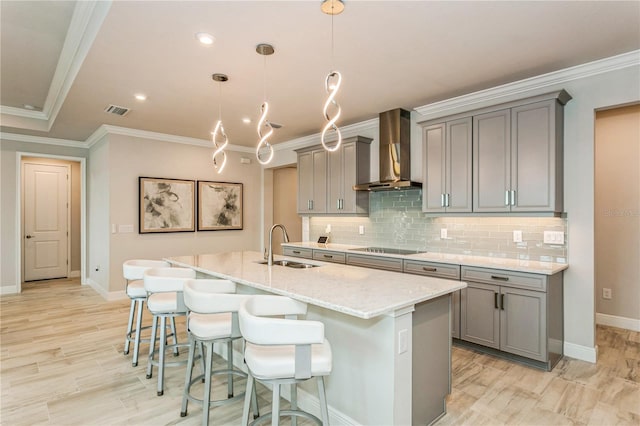 kitchen featuring wall chimney range hood, gray cabinetry, a sink, crown molding, and recessed lighting