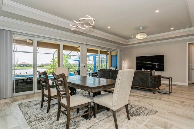 dining space with a raised ceiling, ornamental molding, a chandelier, baseboards, and light wood finished floors