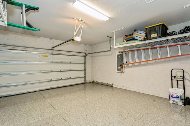 garage featuring a garage door opener, concrete block wall, and electric panel