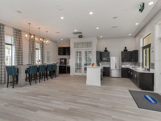 kitchen with appliances with stainless steel finishes, light countertops, tasteful backsplash, ornamental molding, and a sink