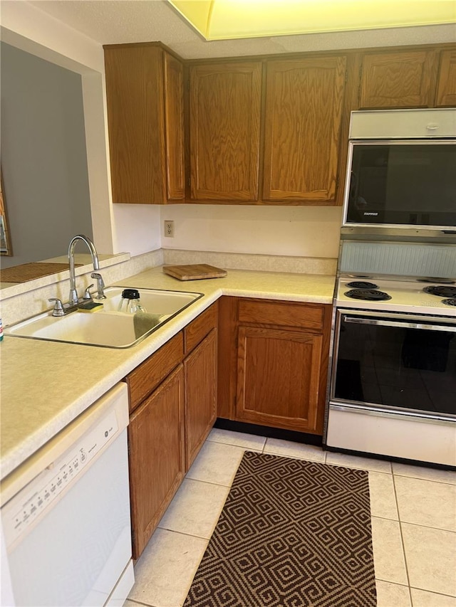 744 Avenida Estancia Unit 144, Venice, FL 34292 - kitchen with light tile patterned floors, brown cabinetry, white appliances, a sink, and light countertops
