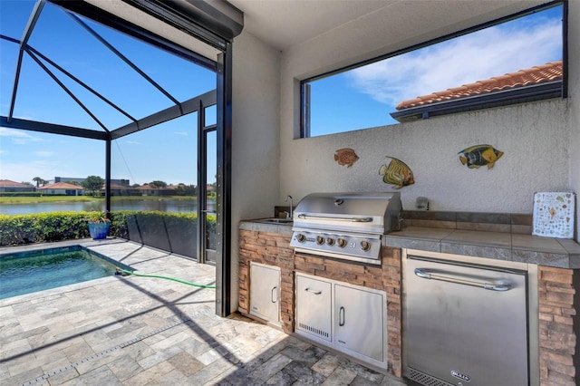 view of patio with grilling area, area for grilling, a water view, a sink, and glass enclosure