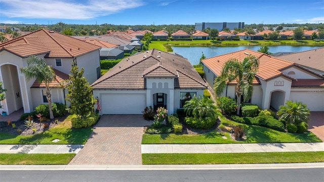 mediterranean / spanish house with a garage, decorative driveway, stucco siding, a tiled roof, and a residential view