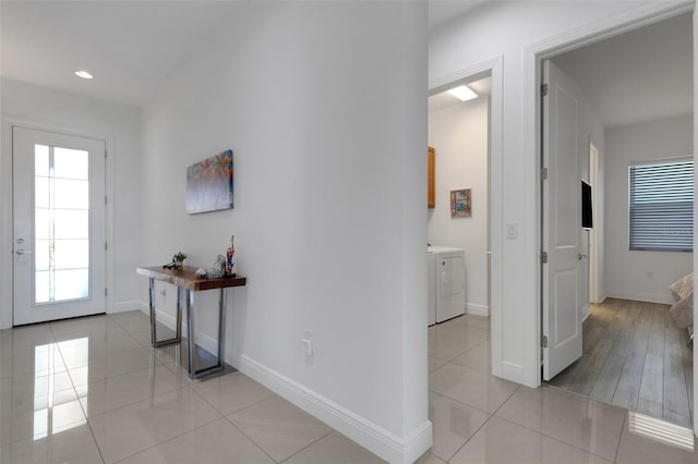 foyer entrance featuring washer and dryer, baseboards, and light tile patterned floors