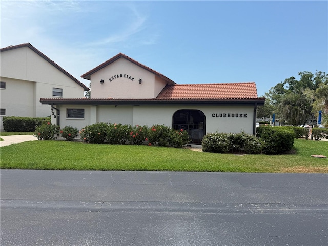 view of front of property with stucco siding, a front lawn, and a tiled roof