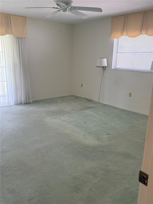 unfurnished room with light colored carpet, a textured ceiling, and ceiling fan