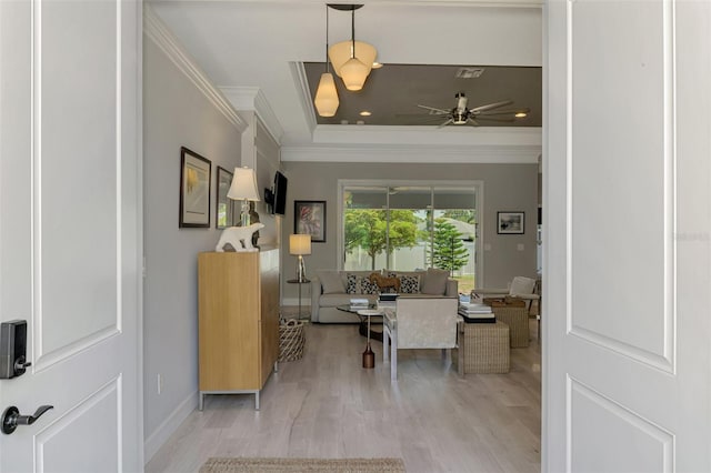 foyer featuring light wood finished floors, ornamental molding, a ceiling fan, a tray ceiling, and baseboards