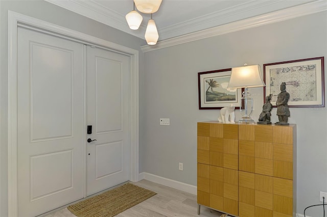 foyer entrance featuring crown molding, light wood-style floors, and baseboards