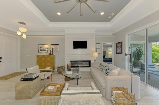 living room featuring a tray ceiling, plenty of natural light, a ceiling fan, and crown molding