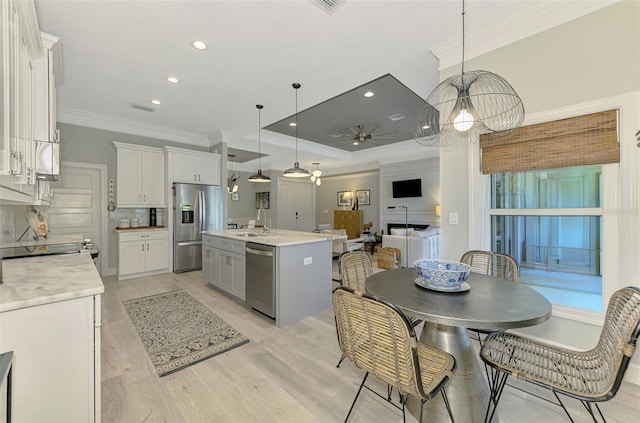 kitchen with appliances with stainless steel finishes, crown molding, white cabinetry, light countertops, and a ceiling fan