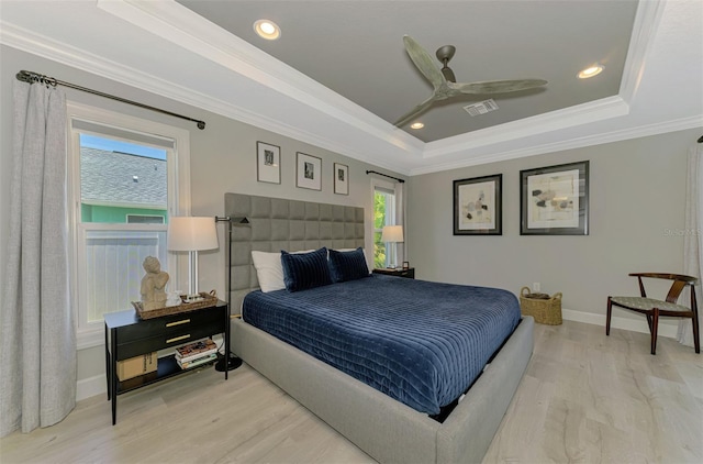 bedroom featuring a raised ceiling, light wood finished floors, crown molding, baseboards, and ceiling fan