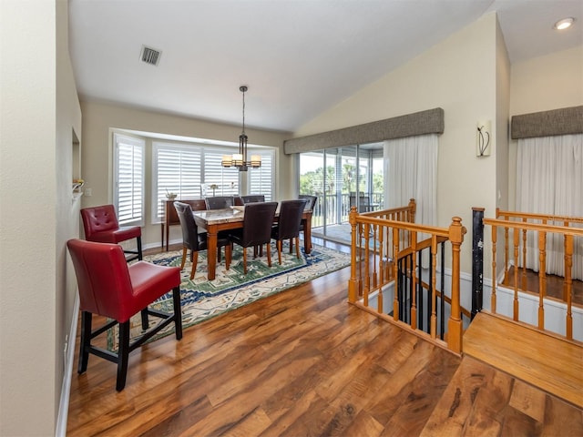 dining room featuring lofted ceiling, wood finished floors, visible vents, an inviting chandelier, and baseboards