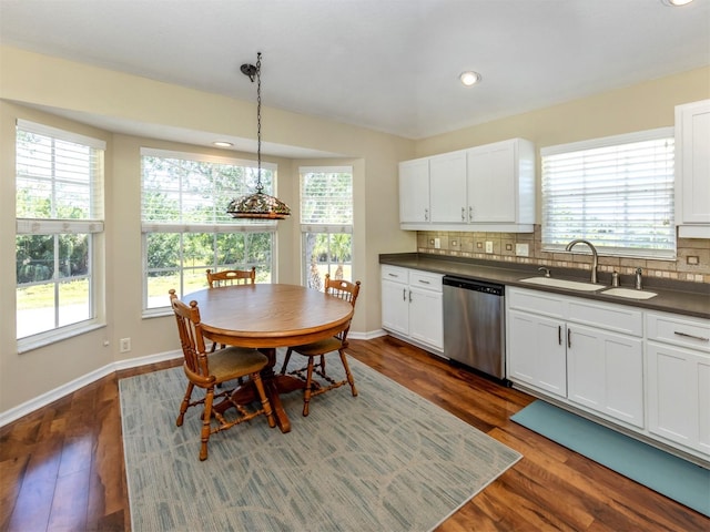 kitchen featuring backsplash, dark countertops, stainless steel dishwasher, and a sink