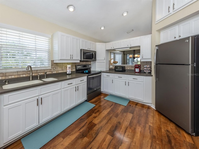 kitchen with a sink, backsplash, dark countertops, and appliances with stainless steel finishes