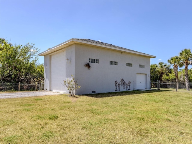 view of side of property with fence, a garage, stucco siding, an outbuilding, and a lawn