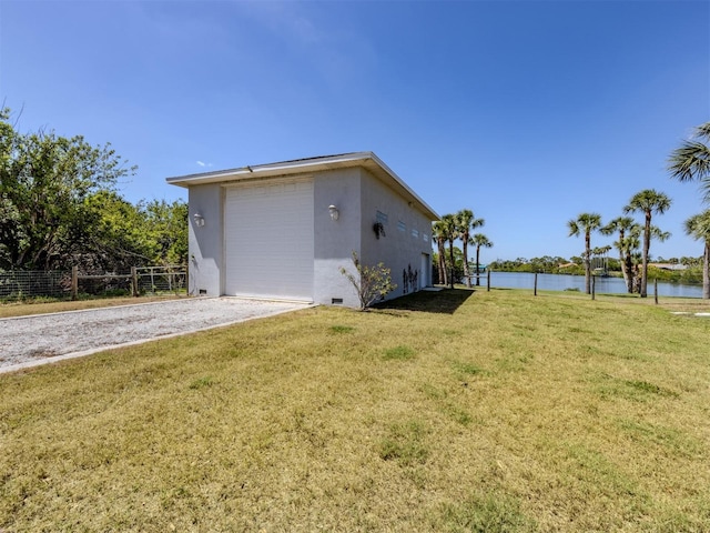 view of home's exterior with stucco siding, a water view, fence, and a lawn