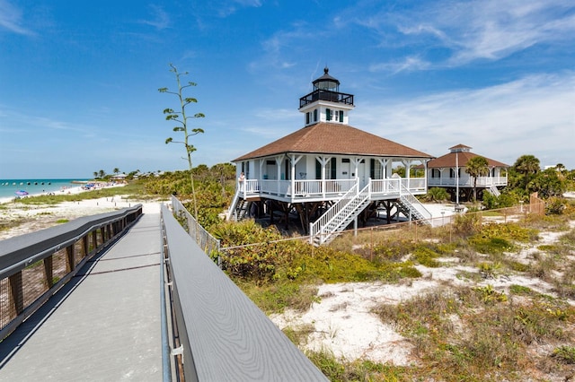 view of property's community with stairs, a water view, and a beach view