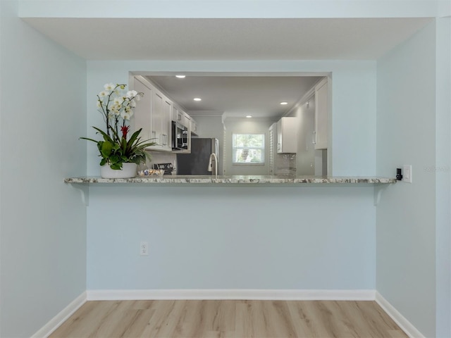 kitchen with appliances with stainless steel finishes, light wood-type flooring, white cabinetry, and recessed lighting