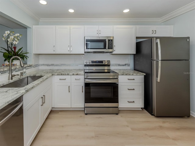 kitchen with stainless steel appliances, a sink, crown molding, white cabinetry, and light stone counters