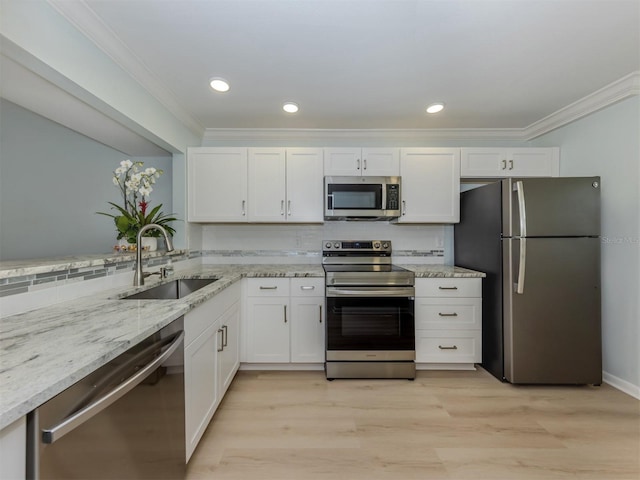 kitchen featuring appliances with stainless steel finishes, a sink, light stone counters, ornamental molding, and white cabinetry