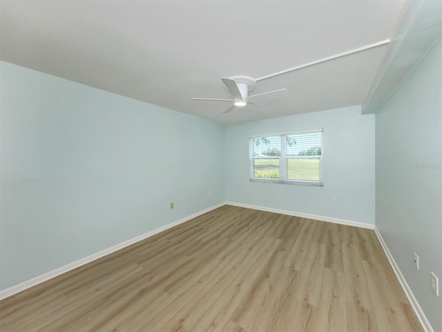 spare room featuring wood finished floors, a ceiling fan, and baseboards