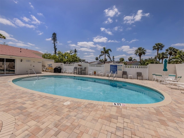 community pool with fence and a patio area