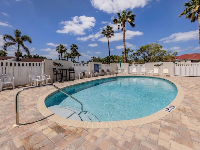 community pool with fence and a patio