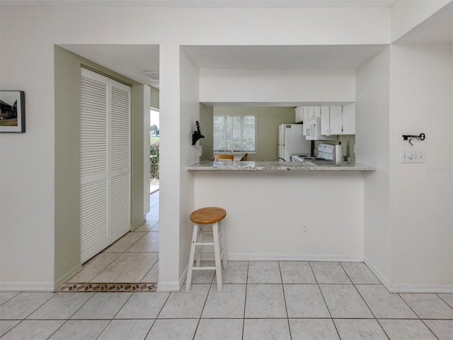 232 Cerromar Way Unit 38, Venice, FL 34293 - kitchen featuring white appliances, light tile patterned floors, light countertops, and white cabinets