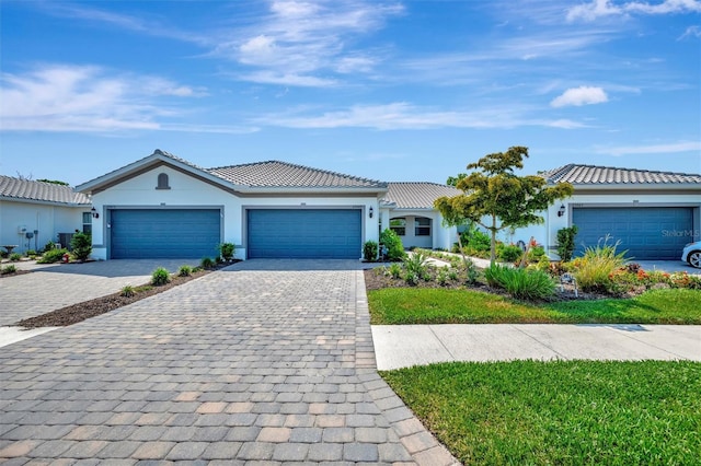 25069 Pearl Lake Cir, Englewood, FL 34223 - ranch-style house featuring decorative driveway, stucco siding, an attached garage, and a tiled roof