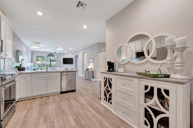 25069 Pearl Lake Cir, Englewood, FL 34223 - kitchen with stainless steel appliances, open floor plan, white cabinets, light wood-style floors, and recessed lighting