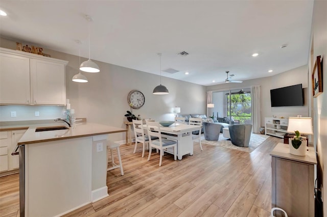 25069 Pearl Lake Cir, Englewood, FL 34223 - kitchen with a sink, open floor plan, light wood finished floors, white cabinetry, and a ceiling fan