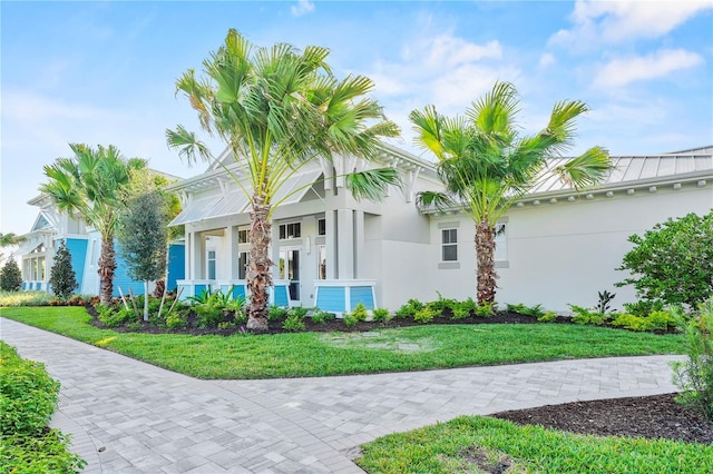 25069 Pearl Lake Cir, Englewood, FL 34223 - view of front of house with stucco siding, a front yard, a standing seam roof, and metal roof
