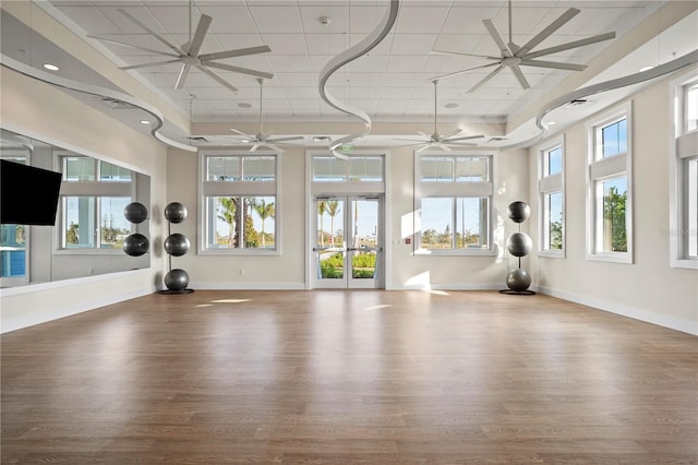 25069 Pearl Lake Cir, Englewood, FL 34223 - workout area with a ceiling fan, baseboards, wood finished floors, healthy amount of natural light, and a towering ceiling