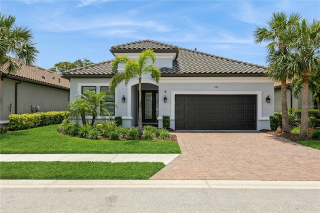mediterranean / spanish home featuring a garage, a tiled roof, decorative driveway, and stucco siding
