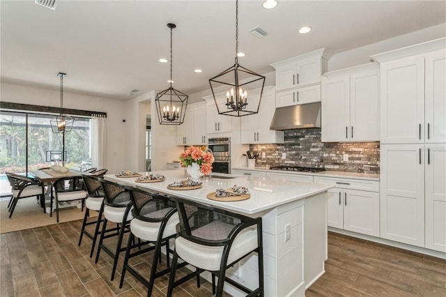 kitchen featuring under cabinet range hood, stainless steel appliances, a chandelier, recessed lighting, and light countertops