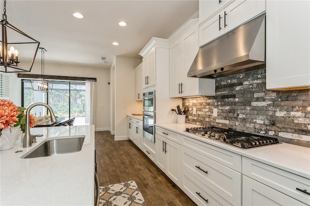 kitchen with under cabinet range hood, stainless steel appliances, a chandelier, a sink, and light countertops