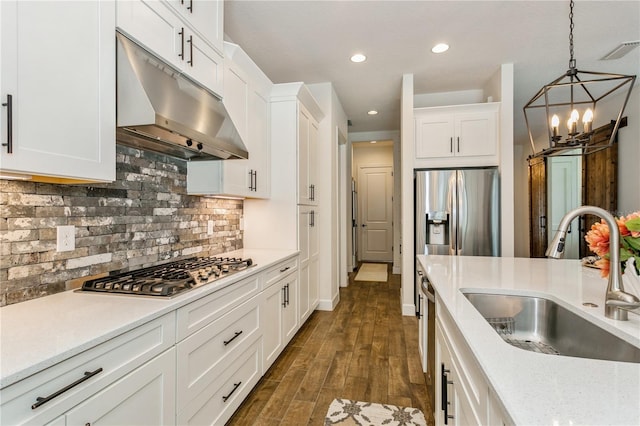kitchen featuring under cabinet range hood, a sink, appliances with stainless steel finishes, white cabinets, and tasteful backsplash