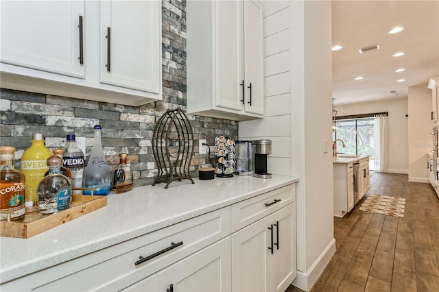 bar featuring baseboards, decorative backsplash, dark wood-style flooring, recessed lighting, and a sink