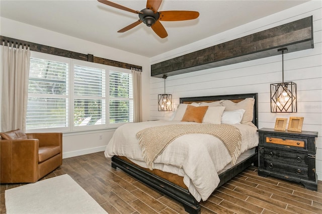 bedroom with baseboards, wood finished floors, wooden walls, and a ceiling fan