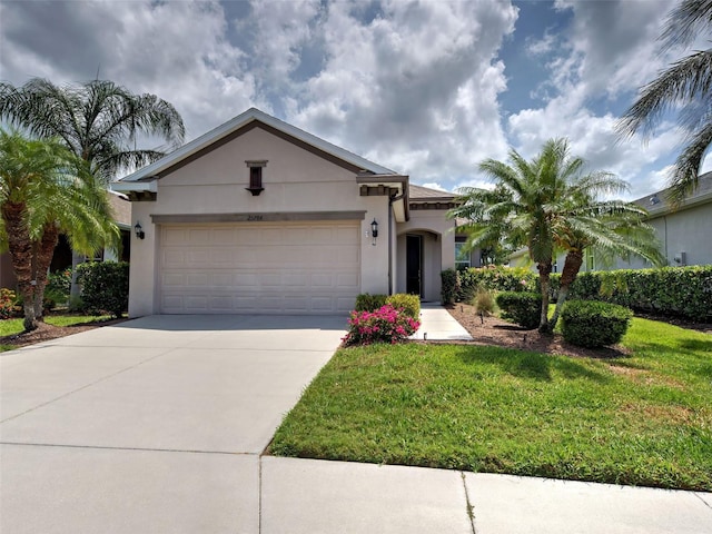 25784 Grayton Ave, Englewood, FL 34223 - view of front of property featuring stucco siding, driveway, an attached garage, and a front lawn