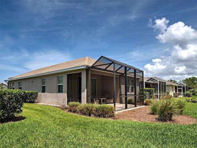 25784 Grayton Ave, Englewood, FL 34223 - back of property with stucco siding, a yard, and glass enclosure