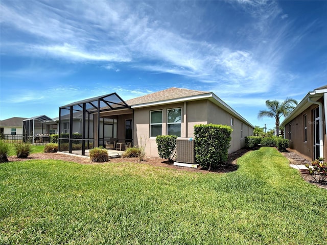 25784 Grayton Ave, Englewood, FL 34223 - rear view of property with central AC unit, stucco siding, a yard, and glass enclosure