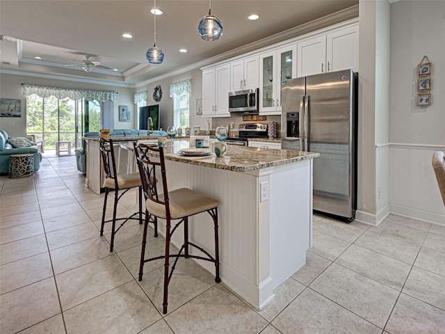 25784 Grayton Ave, Englewood, FL 34223 - kitchen featuring stainless steel appliances, ornamental molding, light stone countertops, a kitchen breakfast bar, and decorative backsplash