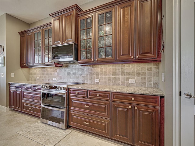 515 Sawgrass Bridge Rd, Venice, FL 34292 - kitchen with appliances with stainless steel finishes, decorative backsplash, light stone counters, and glass insert cabinets