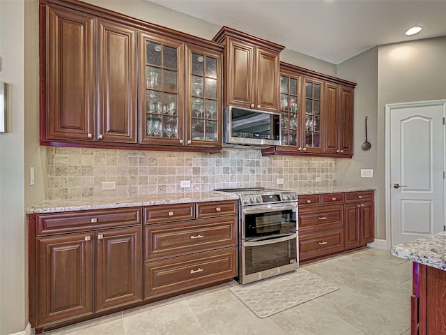 515 Sawgrass Bridge Rd, Venice, FL 34292 - kitchen with stainless steel appliances, decorative backsplash, light stone countertops, and glass insert cabinets
